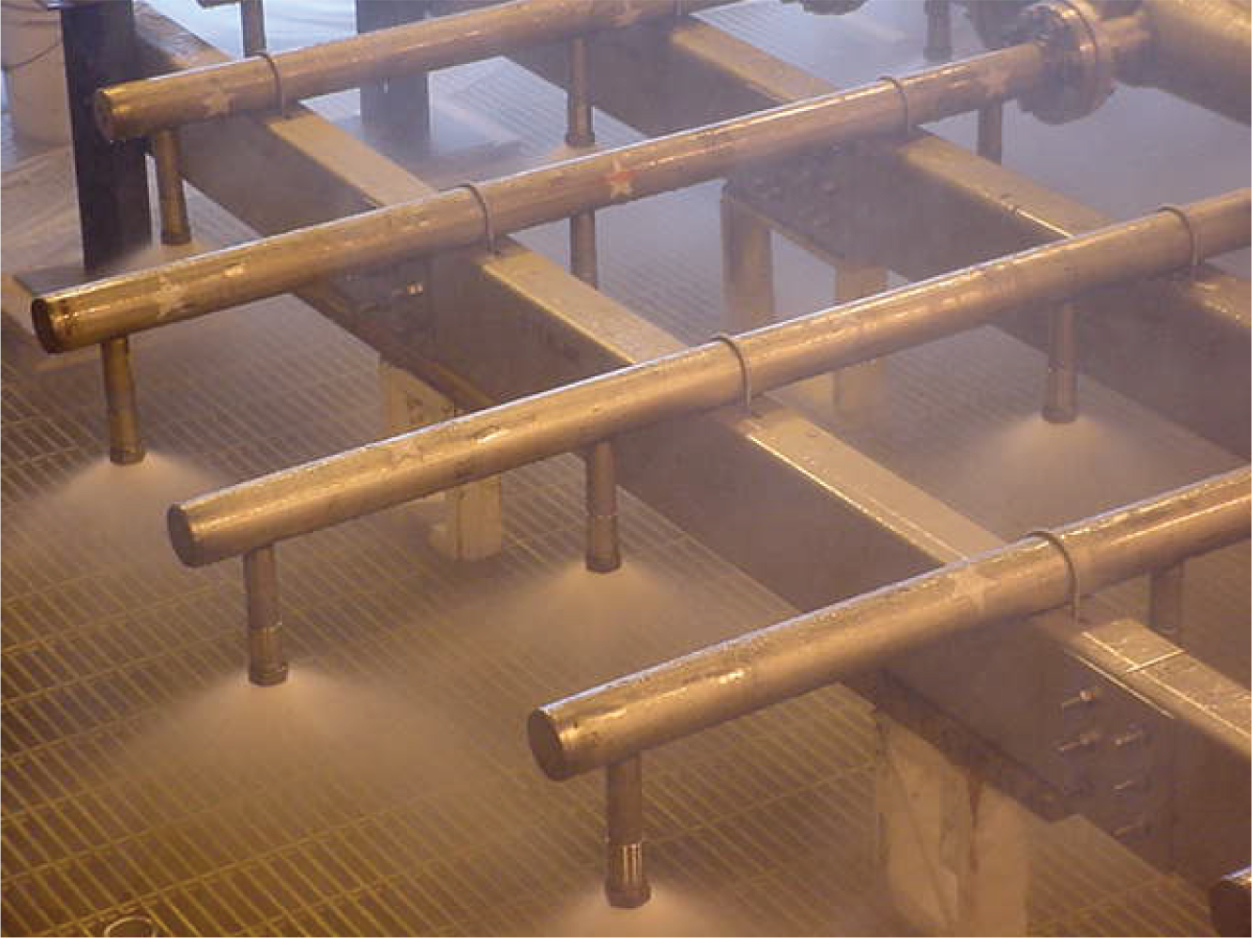 A photographic image of water spray distributors. It consists of a header pipe and laterals supply liquid to spray nozzles arranged in a pattern.