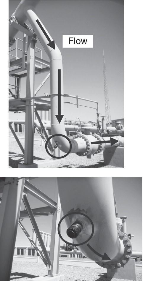 An upper section features a long, curved pipeline labelled Flow, with arrows indicating downward and upward movement. A larger circular flange connects the pipe to a vertical support structure. Above, a tall tower and various industrial elements are visible, suggesting a processing or storage facility. The lower section reveals a close-up of the pipeline’s junction, highlighting a smaller valve arrangement at the curve’s end. The flange mirrors the one above, emphasizing the connection between different pipeline segments in an industrial setting.