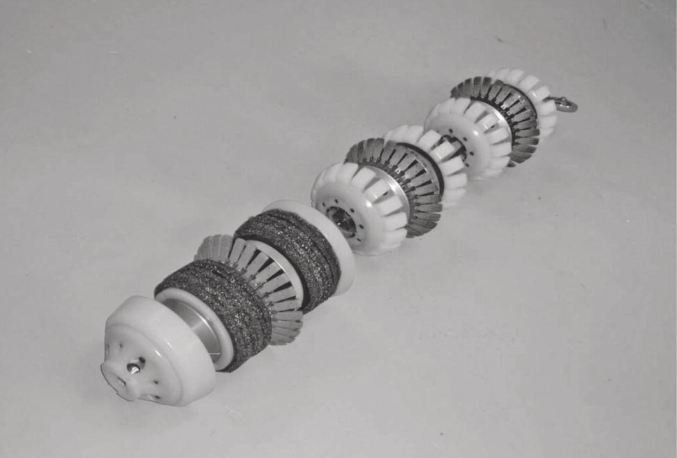An image features a cylindrical object made up of several alternating sections. Each section consists of a combination of circular and cylindrical components, with varying textures and patterns. The ends are rounded, with a central connection point featuring a small metal protrusion. The overall design appears functional, possibly related to mechanical or engineering applications. The distinct arrangement of the parts creates a visually interesting structure, emphasizing symmetry and repetitive patterns. The background is plain, highlighting the object’s details.