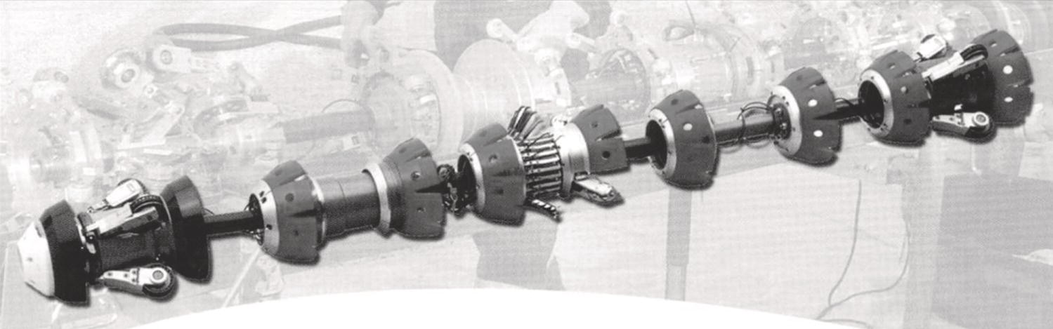An image features a mechanical assembly resembling a flexible robotic arm. Each segment consists of cylindrical components connected in sequence with joints allowing movement. The structure includes gears and actuators integrated into various sections, enhancing functionality. This design is likely employed in complex engineering applications, where precision and adaptability are crucial. The background hints at a workshop environment with additional machinery, suggesting a setting focused on mechanical assembly or robotics development. Overall, the assembly emphasizes innovative engineering solutions.