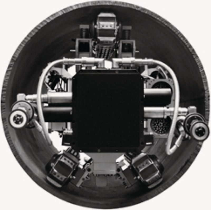 An image features a robotic system designed for use within a cylindrical structure, characterized by a central square component surrounded by various mechanical appendages. Symmetrically placed around the central element are multiple articulated joints equipped with gripping mechanisms. Surrounding the main body, a network of wires and sensors is visible, suggesting an advanced technology for navigation or manipulation tasks within confined spaces.