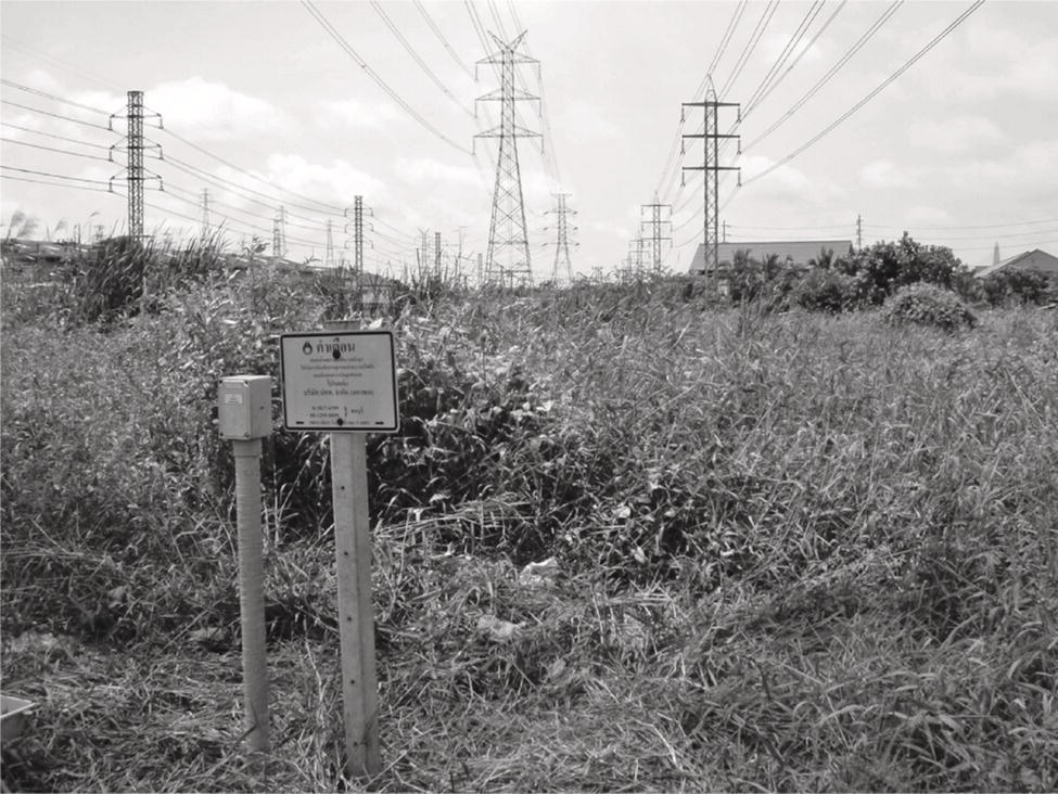 A photograph of a shared corridor featuring high-voltage power lines and underground pipelines, marked by a test station.