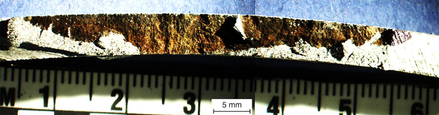 A closer view of a crack in a material, showing a scale ruler underneath for measurement. The label indicates the crack was removed from a second panel.