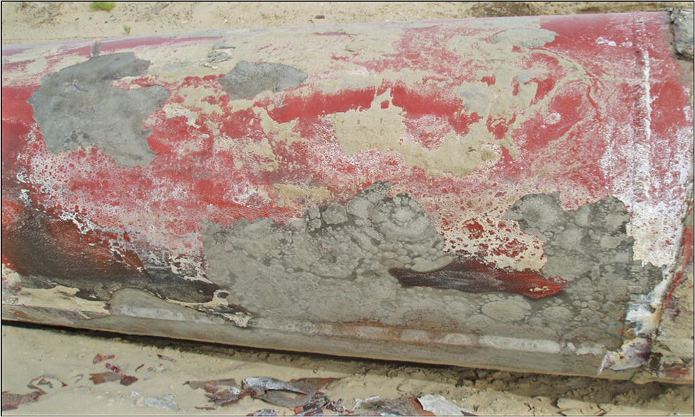 A closer view of a corroded metal surface on a cylindrical object, showing extensive rust and deterioration. The texture is uneven with patches of peeling paint and underlying material exposed.