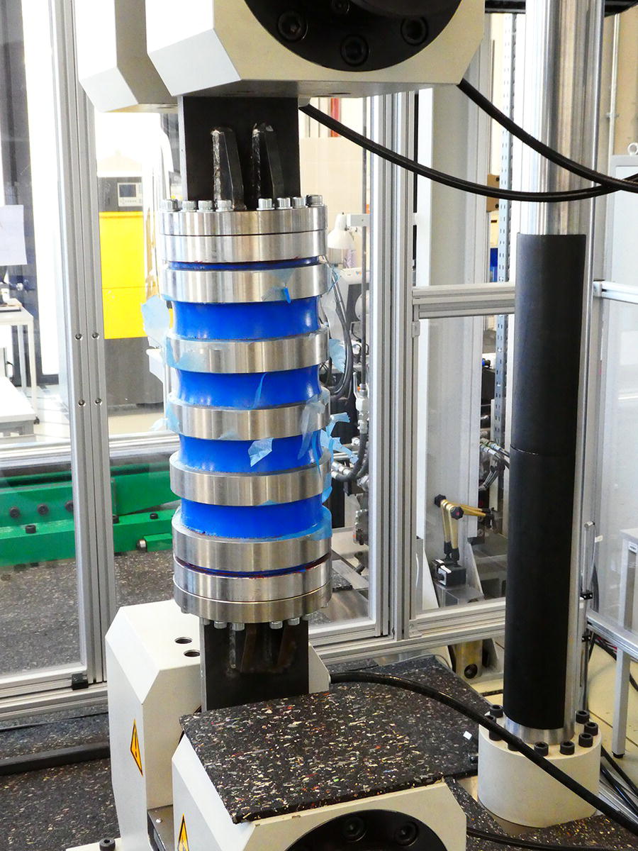 A closer view of a mechanical testing device with cylindrical components stacked vertically. The device is situated in a controlled laboratory setting.